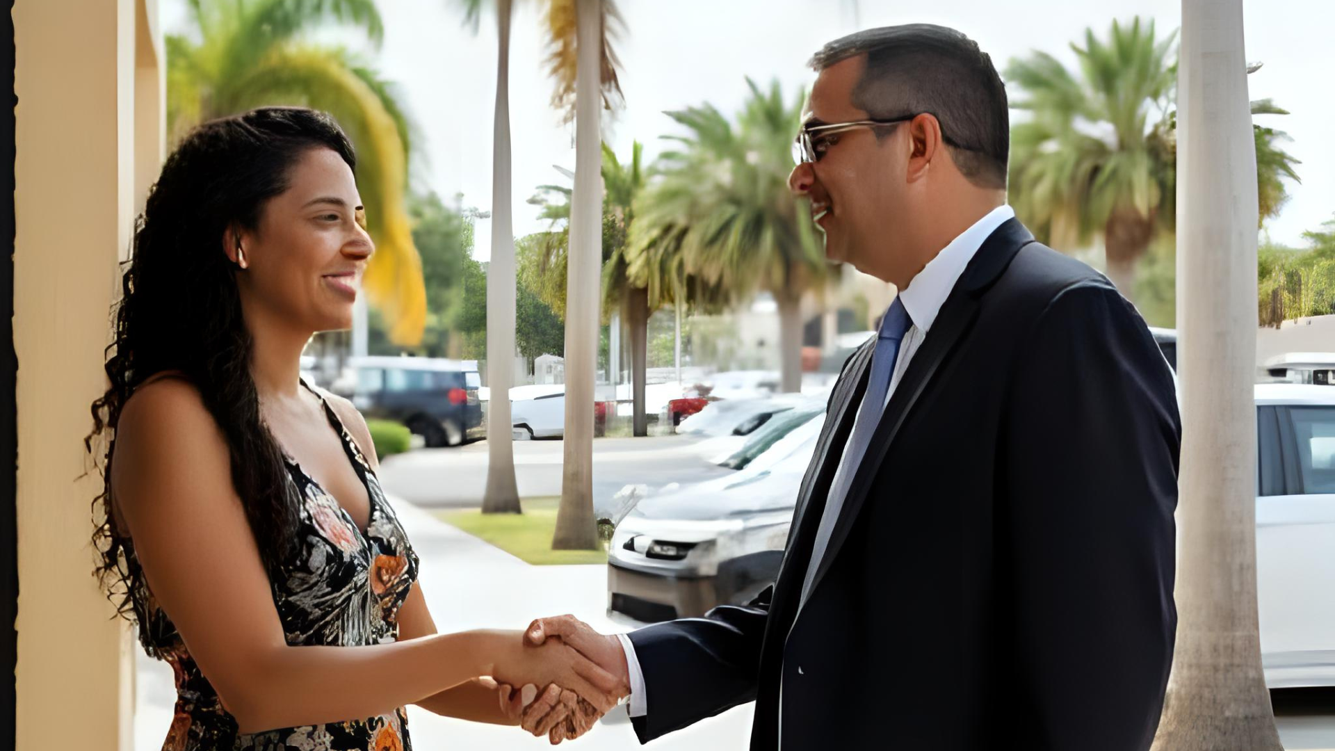 A diverse client shaking hands with a lawyer outside the office, both smiling with genuine relief and gratitude. In the background: Florida sunlight, palm trees, and parked cars suggesting a local street scene. The moment feels victorious, like justice has been served. Style: realistic photography, cinematic depth, hopeful tone.